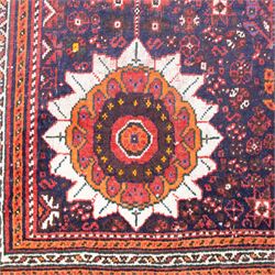 Qashqai wool carpet, red diamond-shaped field decorated with three stepped pole medallions, floral rosettes and scattered stylised motifs, within dark blue spandrels and multiple geometric guard borders