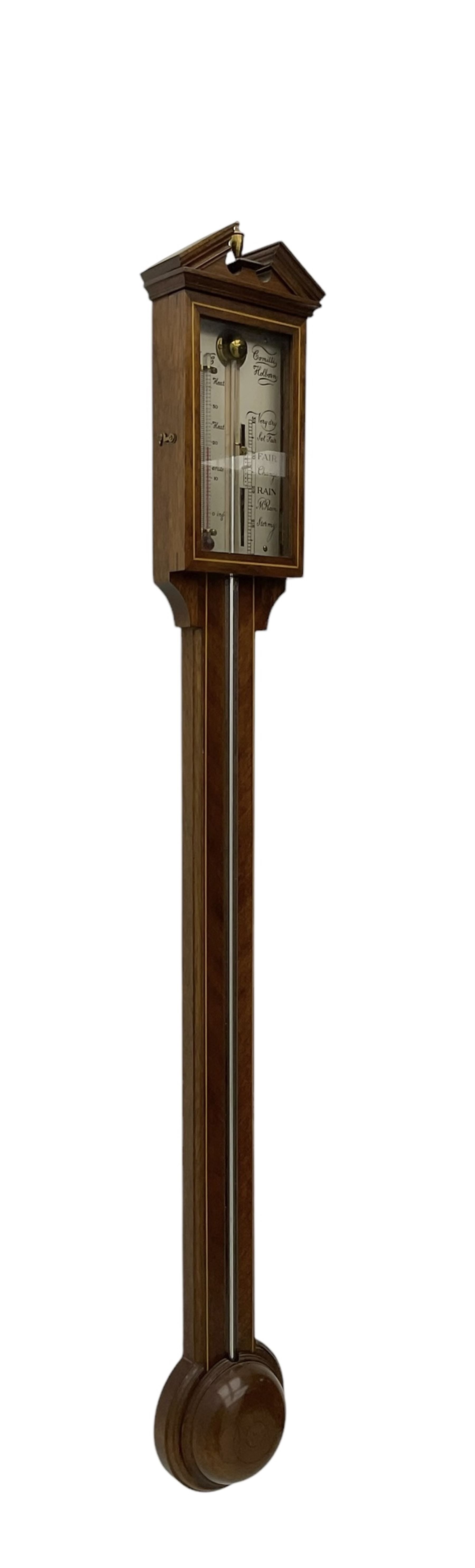 Comitti-20th century mercury stick barometer in an 18th century style mahogany case with satinwood stringing, with a broken pediment, brass finial and round base, silvered register with recording vernier, weather predictions and a centigrade/Fahrenheit spirit thermometer enclosed within a glazed door, visible tube with a bulb cistern and turned mahogany cover.
Mercury clean and present with no air locks.