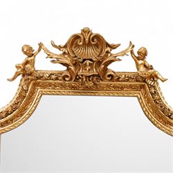 Victorian design gilt framed wall mirror, scrolling shell pediment with curled acanthus leaves flanked by seated putti, the moulded frame decorated with trailing leafy motifs, enclosing bevelled plate, curled acanthus leaf lower corner brackets 