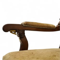 William IV mahogany gentleman's library reclining armchair, leather button upholstered and brass-studded back and seat, above leather-covered arms terminating with carved roundels and foliate scroll-carved ends, underside with brass mechanical trigger reclining lever, the apron with retractable foot rest, supported on lappet carved and turned legs with brass castors, circa 1835