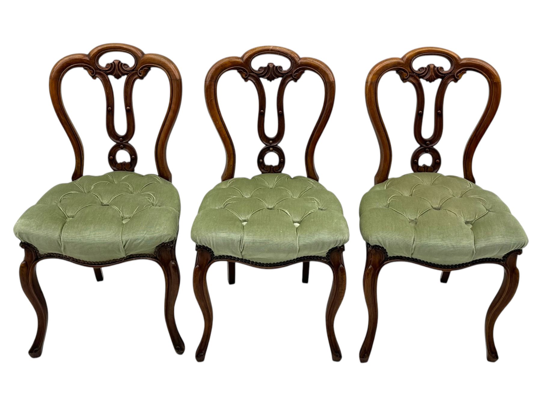 Set of six carved Victorian walnut balloon back dining chairs, button upholstered in green velvet fabric, back with foliate carved decoration supported on scroll form legs 