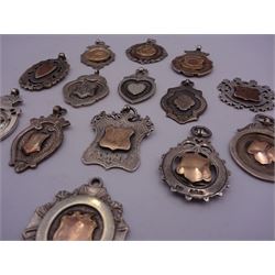 Fourteen silver fobs of various form, mostly early 20th century examples to include a fold faced example detailed with a figure kicking a ball, within a border detailed with orange enamel panels, hallmarked Birmingham 1928, a number of other gold facing examples, and four double sided examples, various hallmarks, dates ranging 1892 to 1950, approximate total weight 4.05 ozt (126 grams)