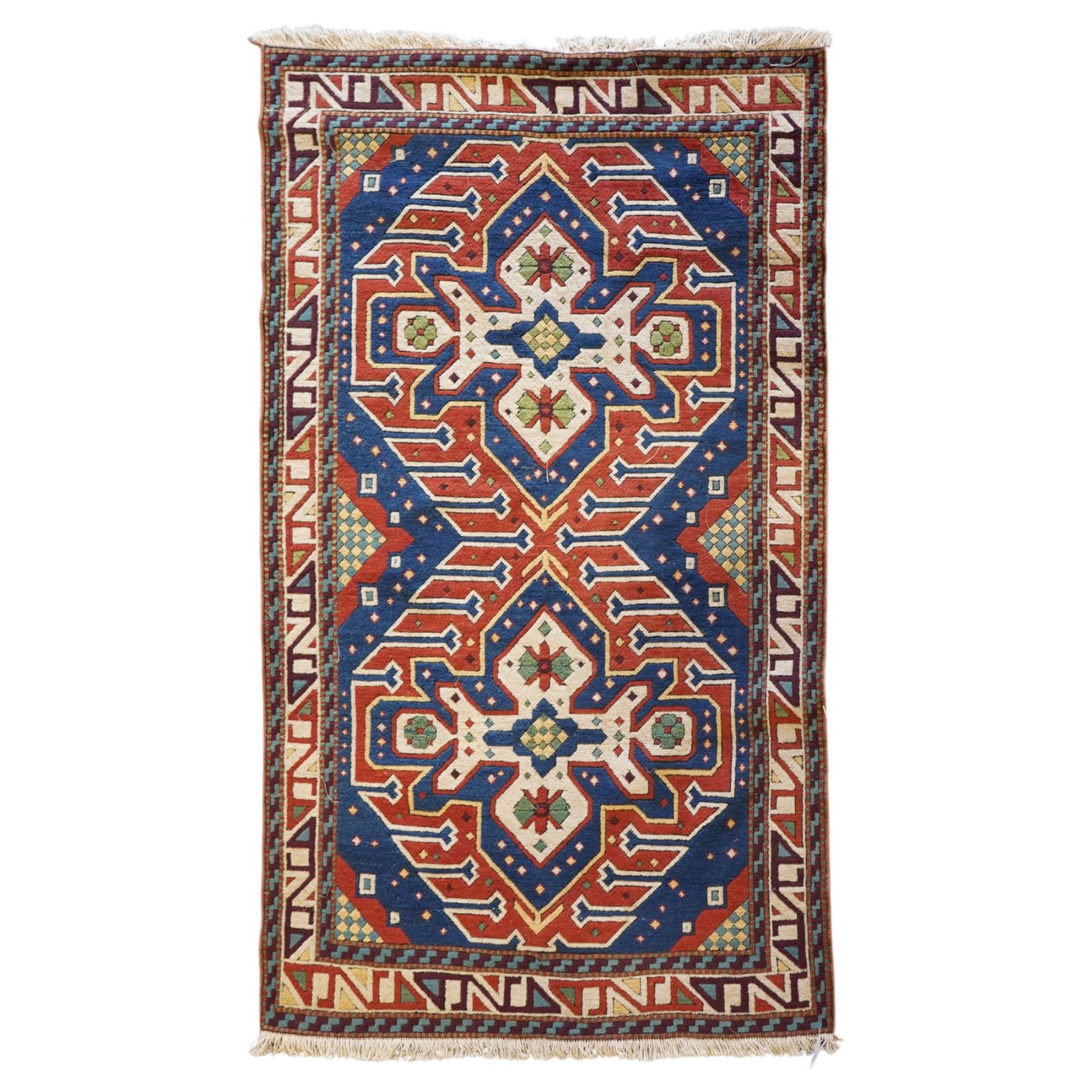 Caucasian Kazak indigo and vermillion ground rug, the geometric field boldly woven with two medallions interspersed with symbolic tribal motifs and shapes, with contrasting ivory guard band