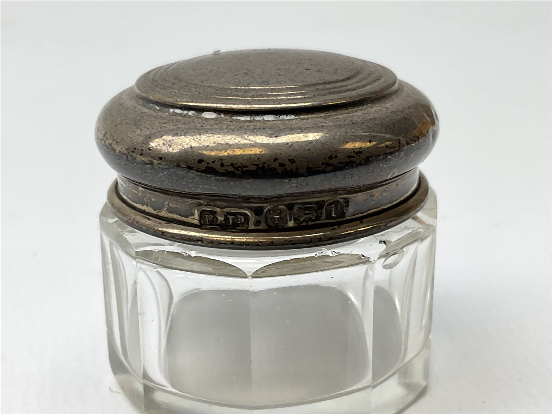 Hallmarked silver top dressing table jars, to include cut glass hobnail example with foliate engraved lid, another 20th century cut glass example with silver engraved screw thread lid, stamped H.S.M Herbert Scott Murdoch, with interior stopper and two smaller glass jars (4)