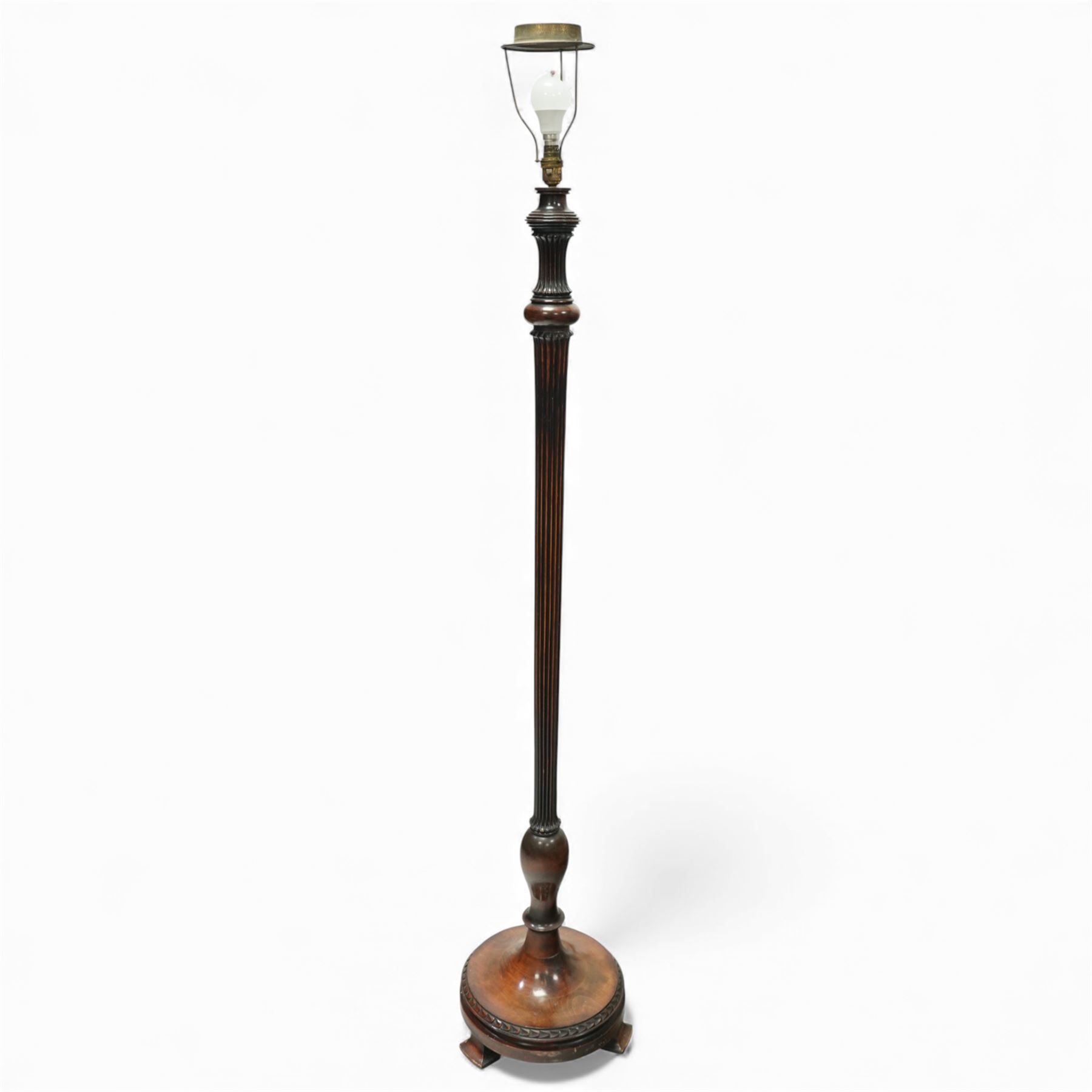 20th century mahogany standard lamp, with fluted tapering column above a turned and moulded circular base, standing on three short bracket supports