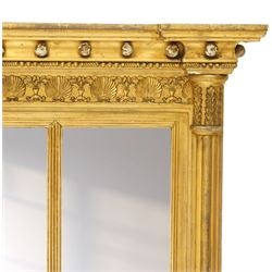 Regency period gilt and gesso framed tripartite overmantel mirror, projecting cavetto cornice applied with globular mounts, the frieze carved with repeating scallop and floral urn motifs, flanked by canted cluster-column pilasters with acanthi capitals, the triple rectangular bevelled plates within reeded slips, on skirted ebonised base
