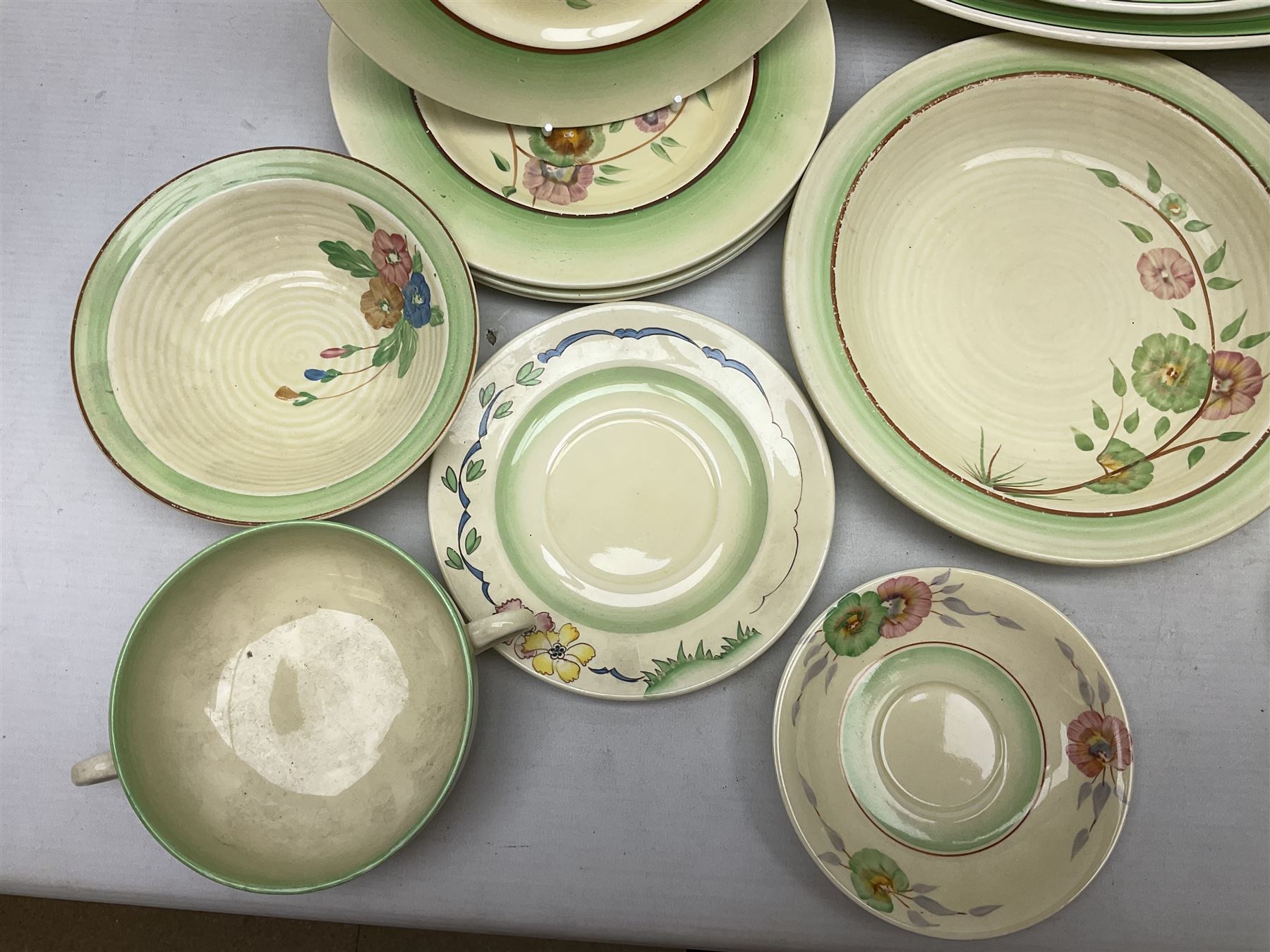 Clarice Cliff for Newport Pottery Corolla pattern tea and dinner wares, comprising triangular bowl, four side plates, two shallow bowls and teacup (a/f), together with a Clarice Cliff Wilkinson twin handled soup bowl and unassociated saucer both decorated with pink and yellow flowers, together with other mid century ceramics comprising Parrott and Company Coronet Ware, and Royal Staffordshire AJ. Wilkinson Ltd dinner wares