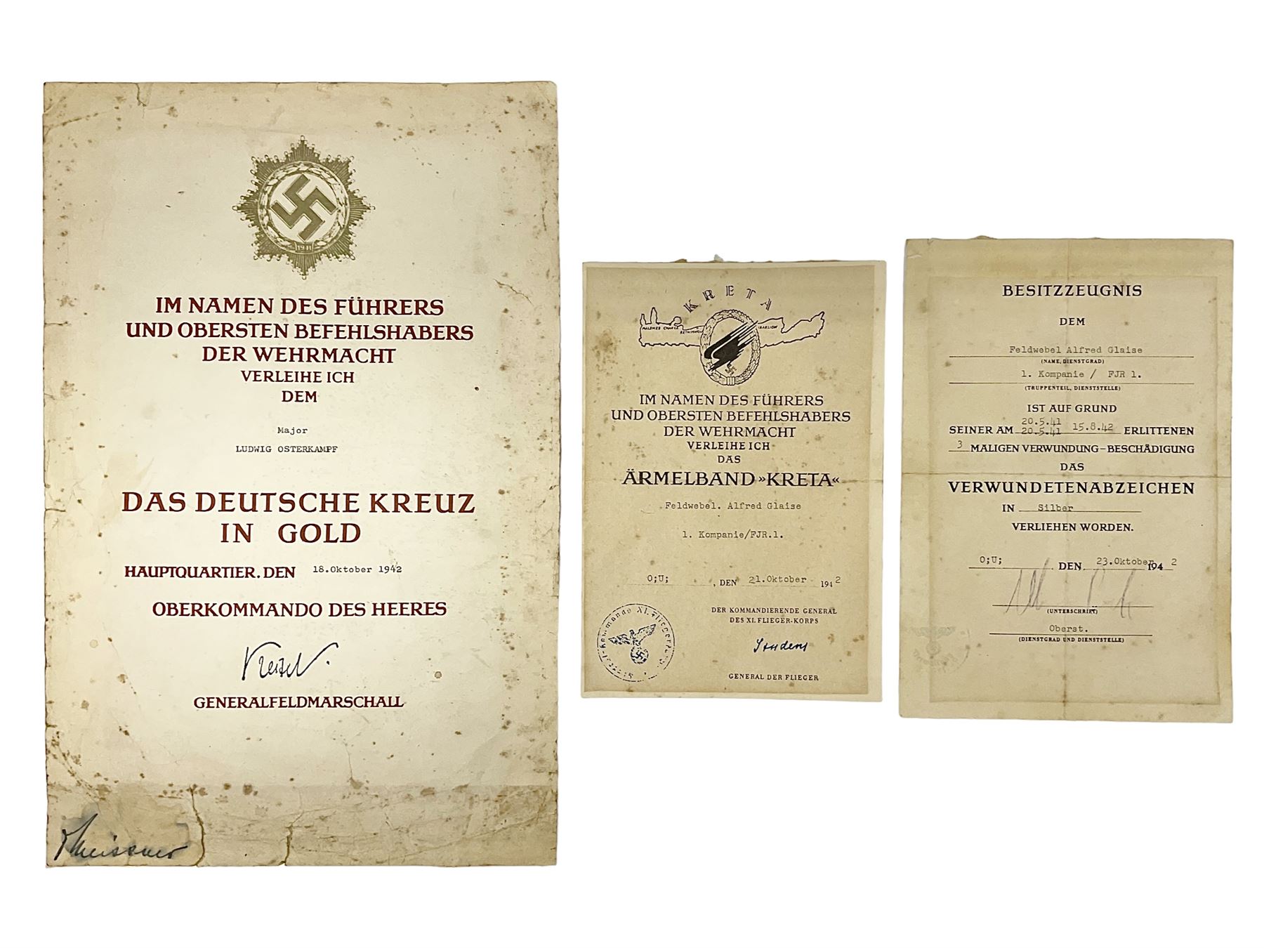 Three German documents dated 1942 - Gold Cross award to Major Ludwig Osterkampf; and Crete wound certificate and cuff title certificate awarded to Feldwebel Alfred Glaise; all unframed (3)
