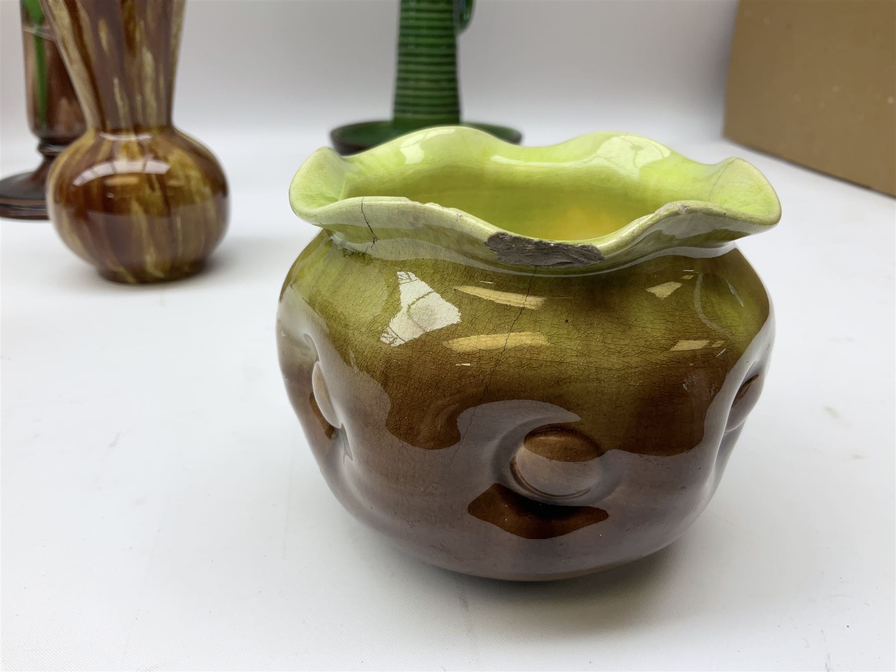Linthorpe pottery vase with crimped rim and ovoid body, Linthorpe jug with high loop handle and crimped spout, a pair of candlesticks with a green, brown glaze and other similar pottery 