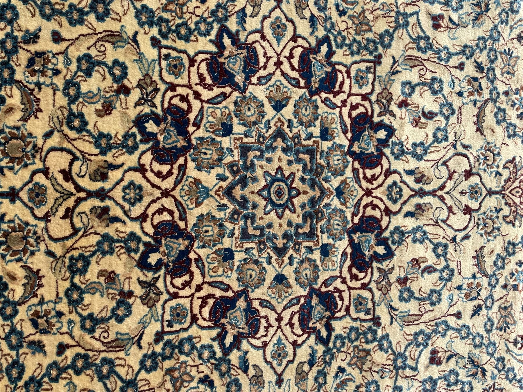 Persian Kashan ivory ground rug, wool with silk inlay, central floral rosette medallion surrounded by trailing flower heads and interlacing leafy branches, the repeating scrolling border decorated with palmettes, within guard stripes