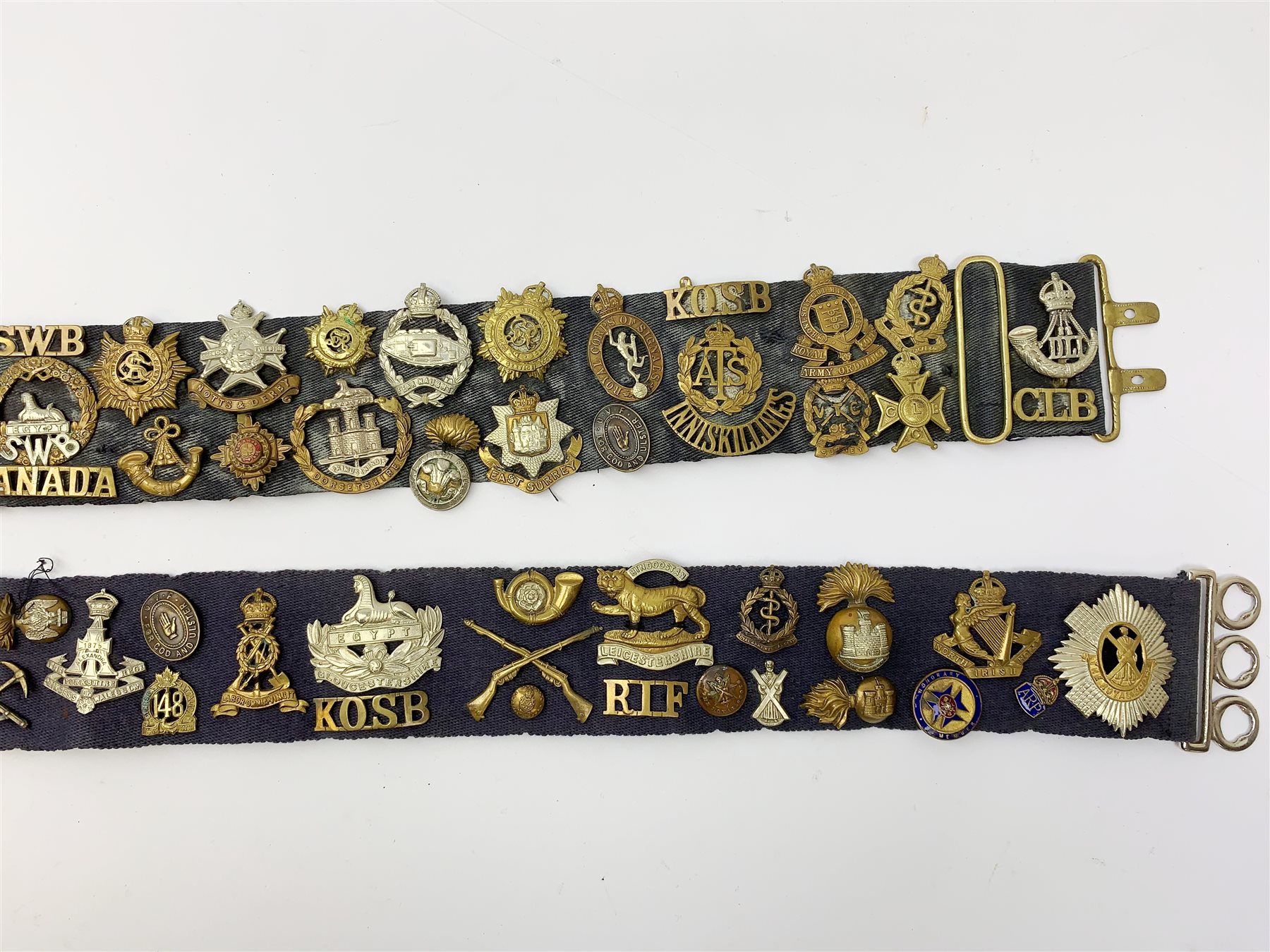 Collection of Glengarry and cap badges, shoulder titles, collar dogs, buttons etc mounted on two military belts, including rare Kitchener's Army Volunteer Training Corps Surrey 1915, two Ulster Volunteer Force (L6521 & L2007), Royal Irish, North Irish Horse, Inniskillings, Royal Irish Rifles, London Irish, London Irish Rifles, Royal Irish Fusiliers, Queen's Own Cameron Highlanders, Royal Scots, 9th Battalion (Glasgow) HLI, Royal Welch Fusiliers, South Wales Borderers, Church Lads Brigade, various regiments and corps, RUC and officer's training corps buttons etc
