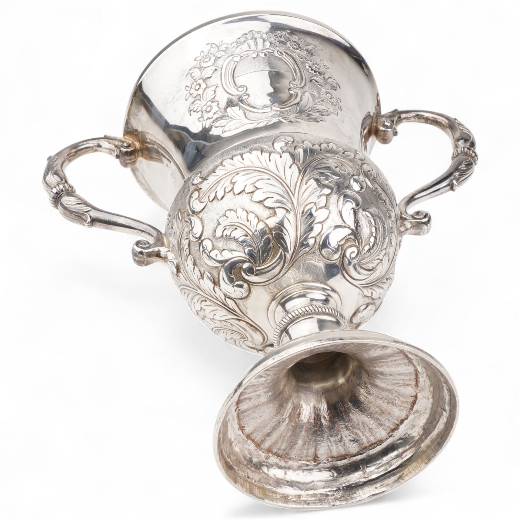 George III silver two handled campana shape cup and cover with pineapple lift, the body with cartouche surrounded by flowers above leaves and scrolls on a pedestal foot with acanthus leaf decoration H29cm London 1764, makers marks rubbed