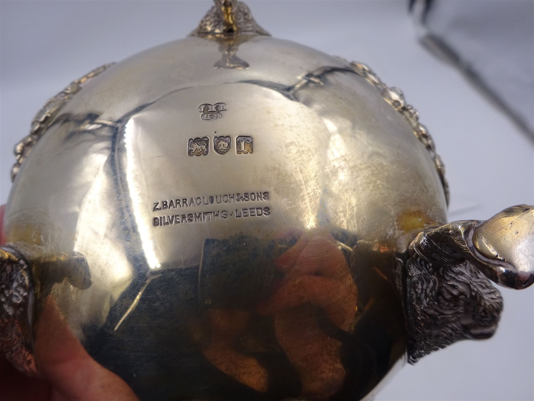 Early 20th century silver open sucrier, of circular form, with fluted gadrooned rim and decorated in relief with floral swags, united by three lion mask mounts and upon three paw feet, hallmarked Z Barraclough & Sons, London 1912, H6cm, D11cm, with similar spoon with lion mask finial, hallmarked London 1912, maker's mark indistinct