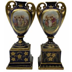 Pair of Vienna style urns, of ovoid form with twin gilt handles, upon a spreading circular foot and plinth base, the bodies decoration with oval panels of dancing classical figures, the whole heightened in gilt, with spurious mark beneath, H21cm