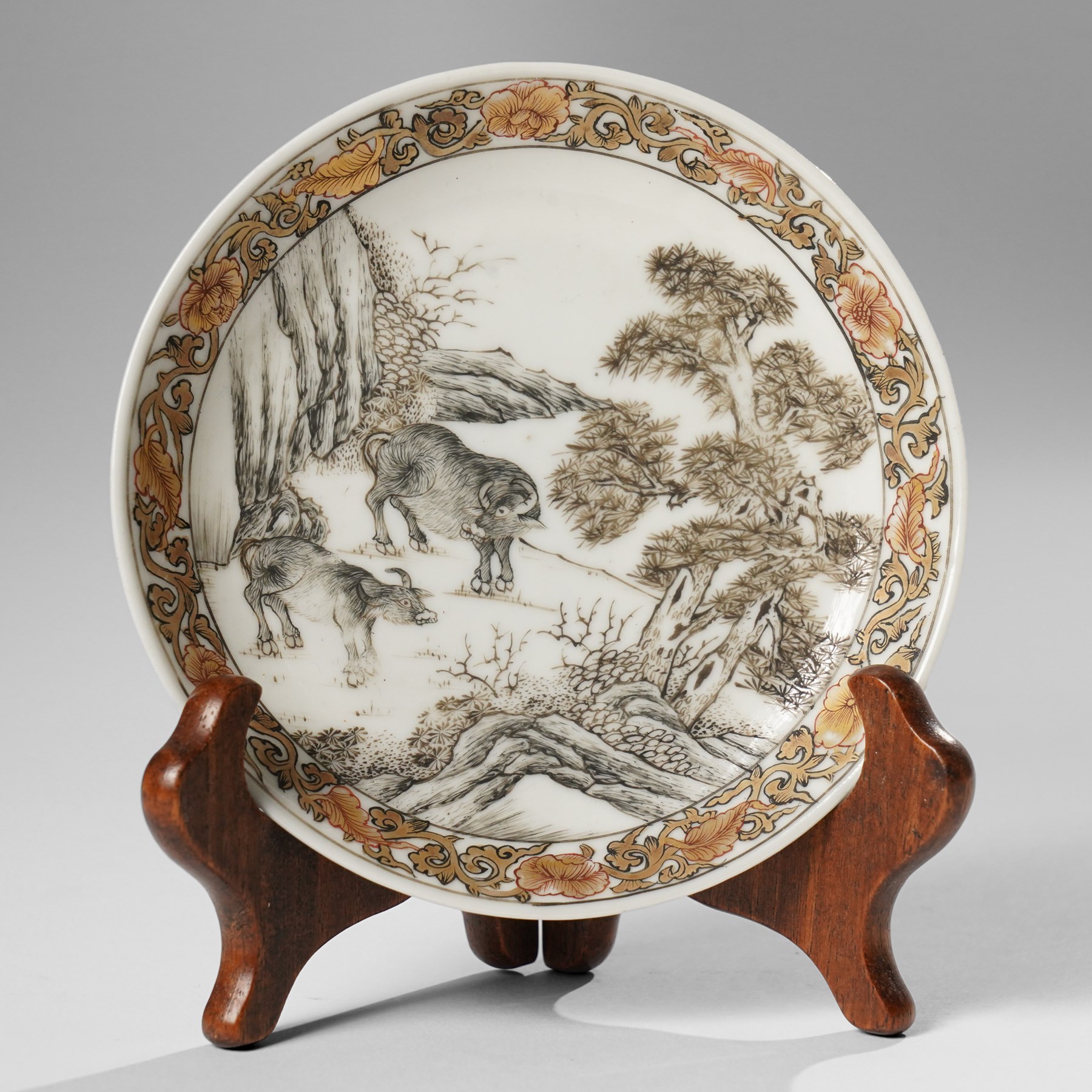 Chinese Yongzheng period saucer, finely painted in grisaille with buffalo within a rocky landscape, the inner rim with iron red and gilt foliate band, D11.5cm