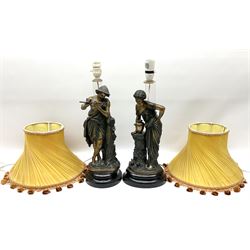 Pair of cast figural lamps, depicting a male piper and a female with an urn, both in a naturalist setting on wooden oval plinths H47, together with  a pair of orange lampshade with frill detail. 