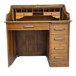 Early 20th century oak roll-top desk, the tambour enclosing pigeon holes and small drawers, the base fitted with slide, a single long drawer and three smaller drawers