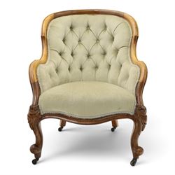 Victorian carved walnut framed armchair with matching stool, the tub-shaped chair with moulded and shaped frame and arm terminals, raised on scrolled cartouche carved supports with scroll feet and castors, buttoned back and sprung seat upholstered in sage green fabric; the small circular footstool with buttoned seat and scroll supports (W36cm H15cm)