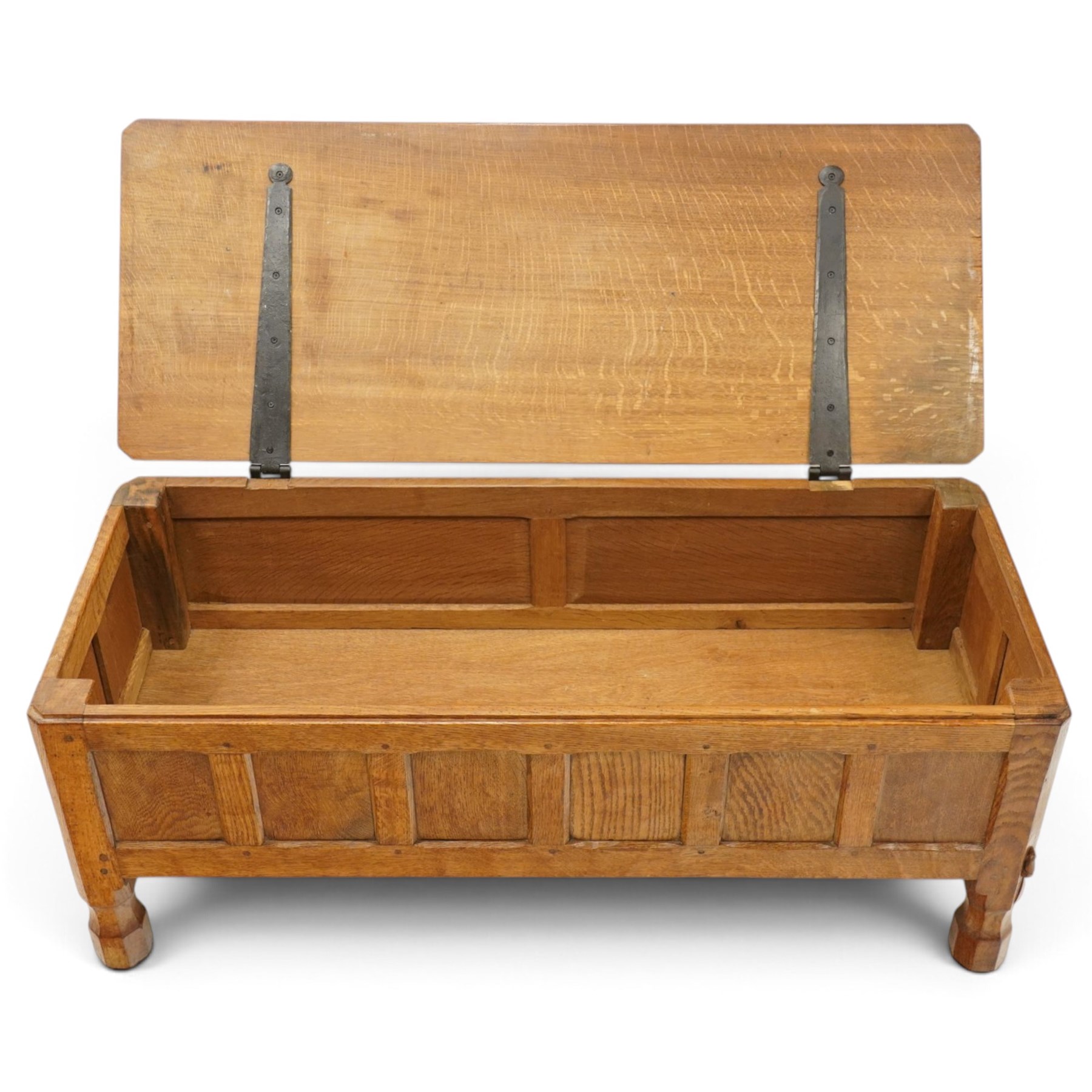 Mouseman - 1950s adzed oak blanket chest of unusual proportions, the rectangular hinged top with canted corners, over a sextuple panelled front, raised on turned octagonal feet, carved with mouse signature, by the workshop of Robert Thompson of Kilburn