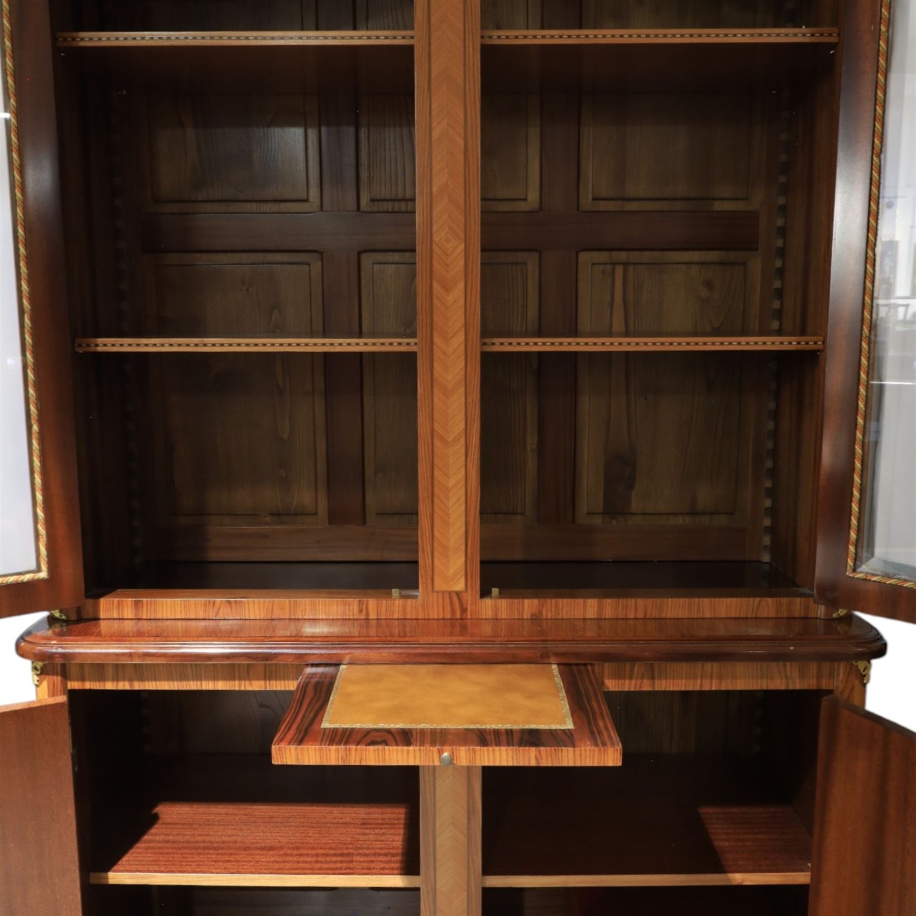 French style marquetry display bookcase, with twin glazed upper doors enclosing shelves, over a cupboard base inlaid with musical instruments and foliate decoration, the interior fitted with mirrored cupboard doors and a pull-out shelf, with gilt metal mounts and banding