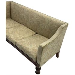 Victorian mahogany framed three-seat settee, upholstered in floral pattern fabric, on turned feet with brass and ceramic castors 