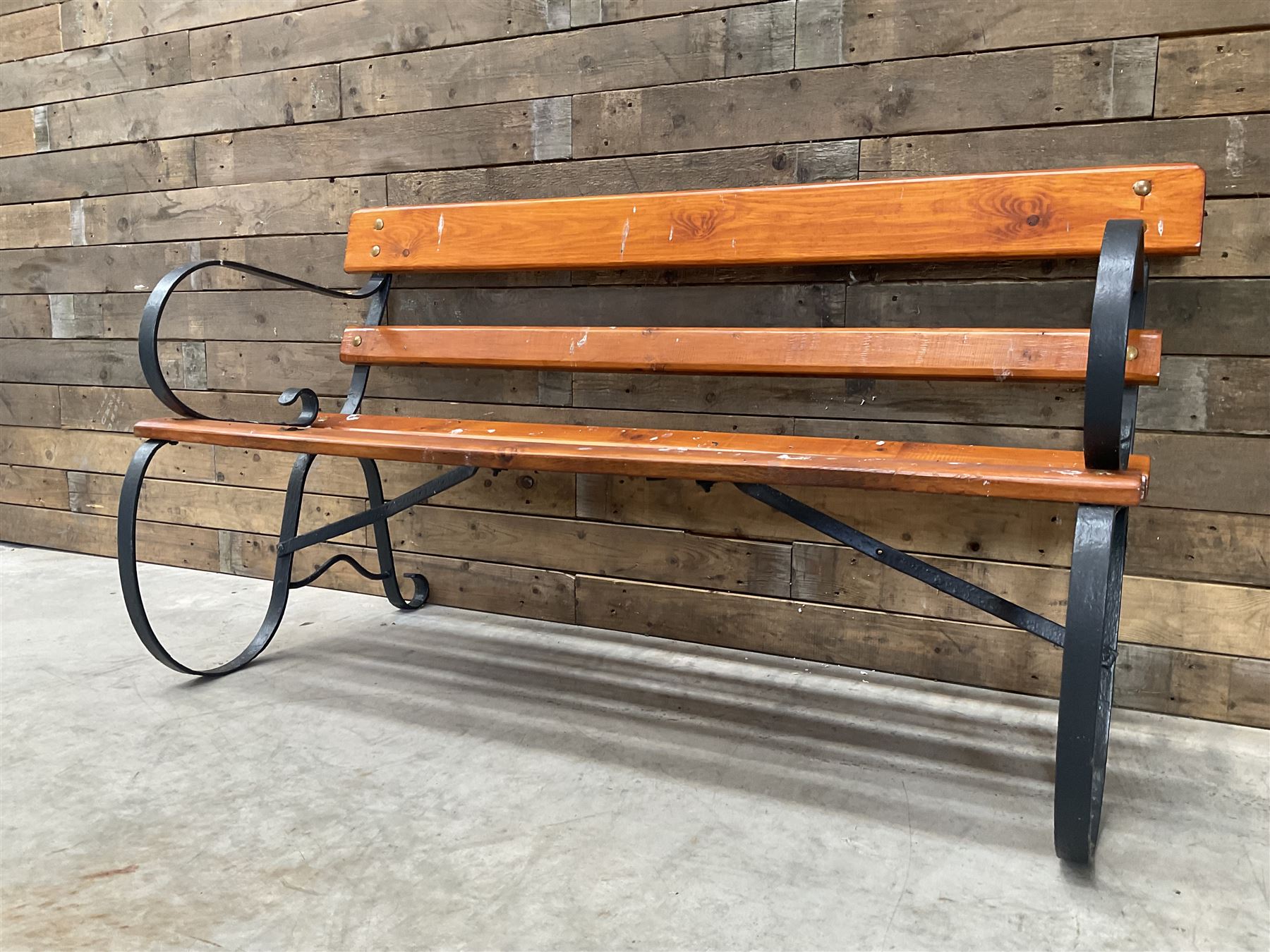 Wrought metal scrollwork and wood slatted garden bench