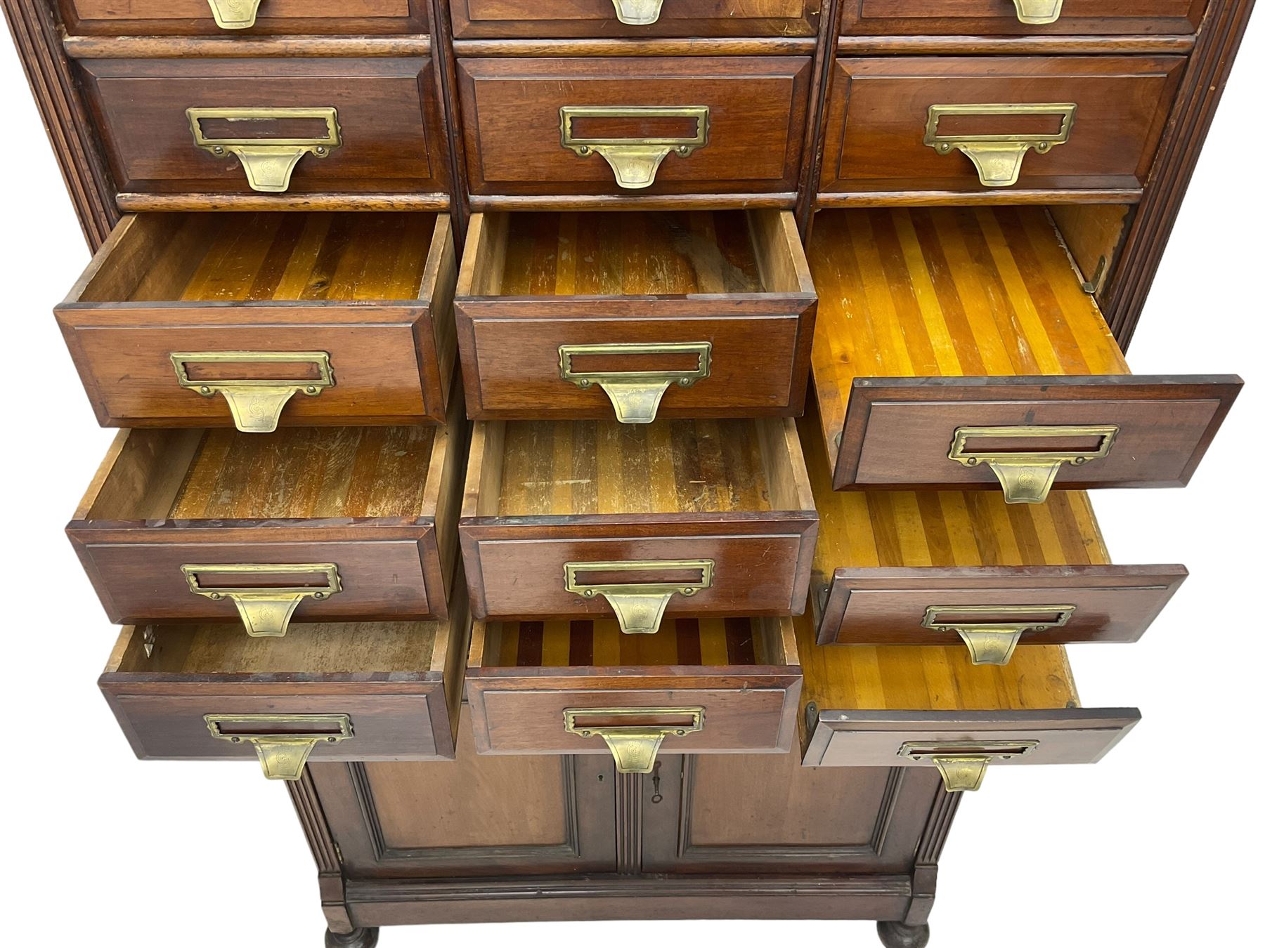 The Shannon Limited - late Victorian walnut filing cabinet, fitted with twenty-four small filing drawers, each with brass handle with label holder, fluted uprights, double cupboard below enclosed by two panelled doors, on turned feet, with brass plaque inscribed 'The Shannon, Limited, Ropemaker St. London, E.C.'