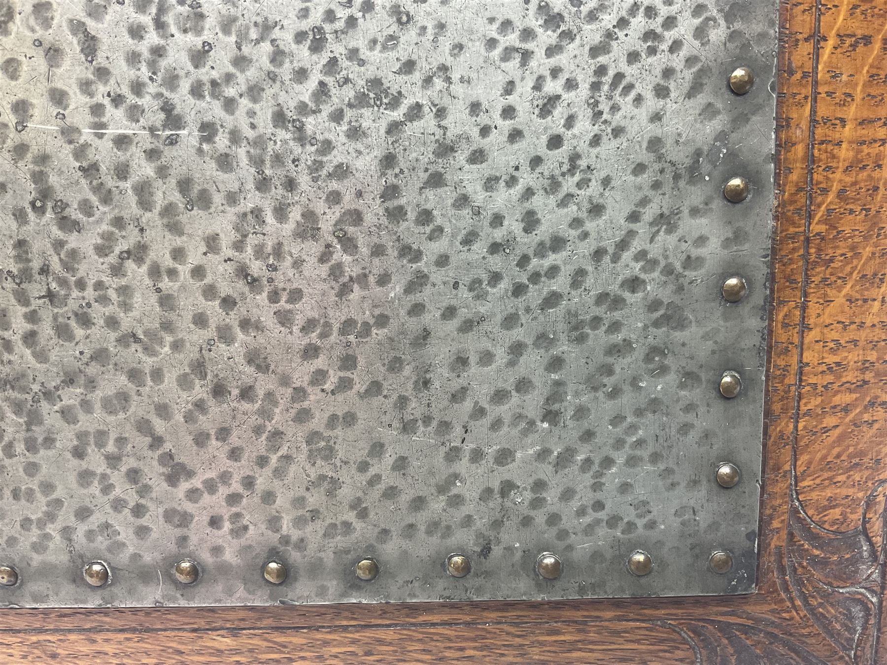 Arts and Crafts oak stand by Arthur Simpson of Kendal, of rectangular form with central hammered pewter panel, surrounded by a border with carved foliate corners, upon two bar supports, bearing label detailed 