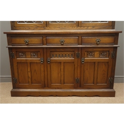  Old Charm oak bookcase display cabinet, projecting cornice, three lead glazed doors enclosing three shelves above cupboard base with three drawers and three cupboards, plinth base, W135cm, H189cm, D46cm  