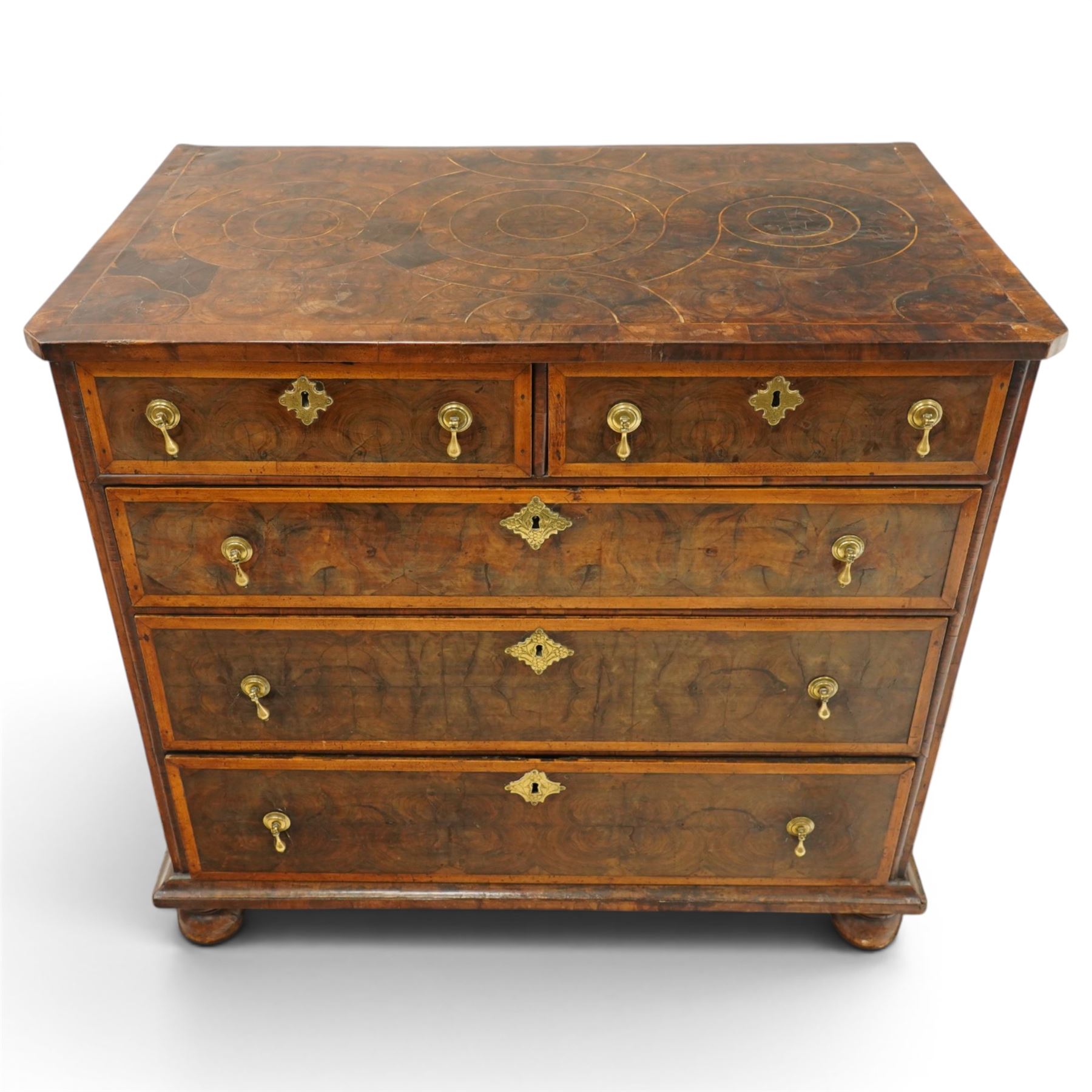 William & Mary period laburnum and walnut oyster-veneered chest, the rectangular top with canted corners and walnut banded edge, profusely decorated with oyster veneer and fruitwood stringing in concentric circles, fitted with two short over three long drawers with fruitwood banding, each fitted with original pressed brass escutcheons and pull handles, lower moulded edge over original bun feet