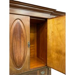Edwardian mahogany wardrobe, break front with projecting moulded cornice, the centre fitted with double cupboard over three short and three long drawers, flanked by two full height doors with oval bevelled mirrors, on turned feet