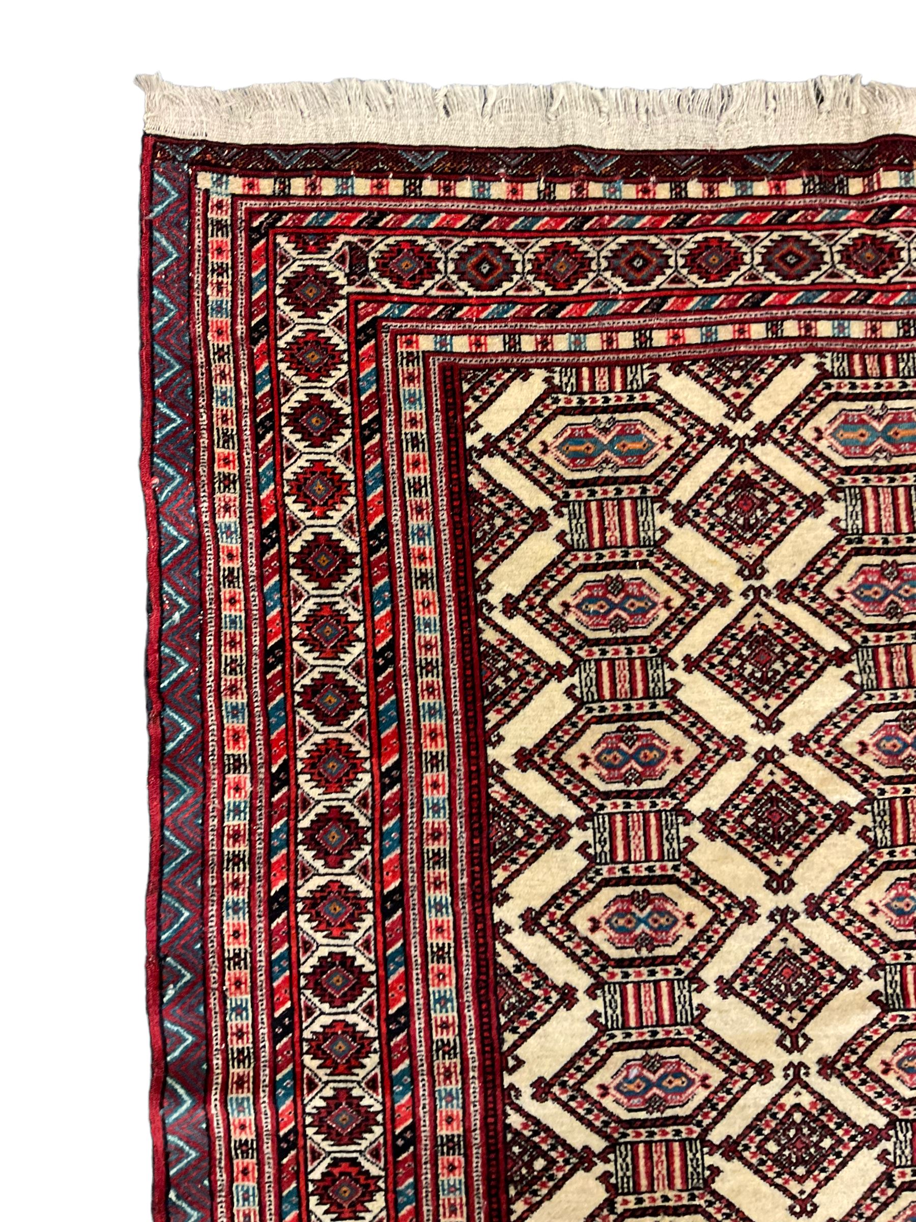 North East Persian Turkoman rug, ivory ground field decorated with repeating Gul motifs, multi-band border decorated with geometric patterns and motifs