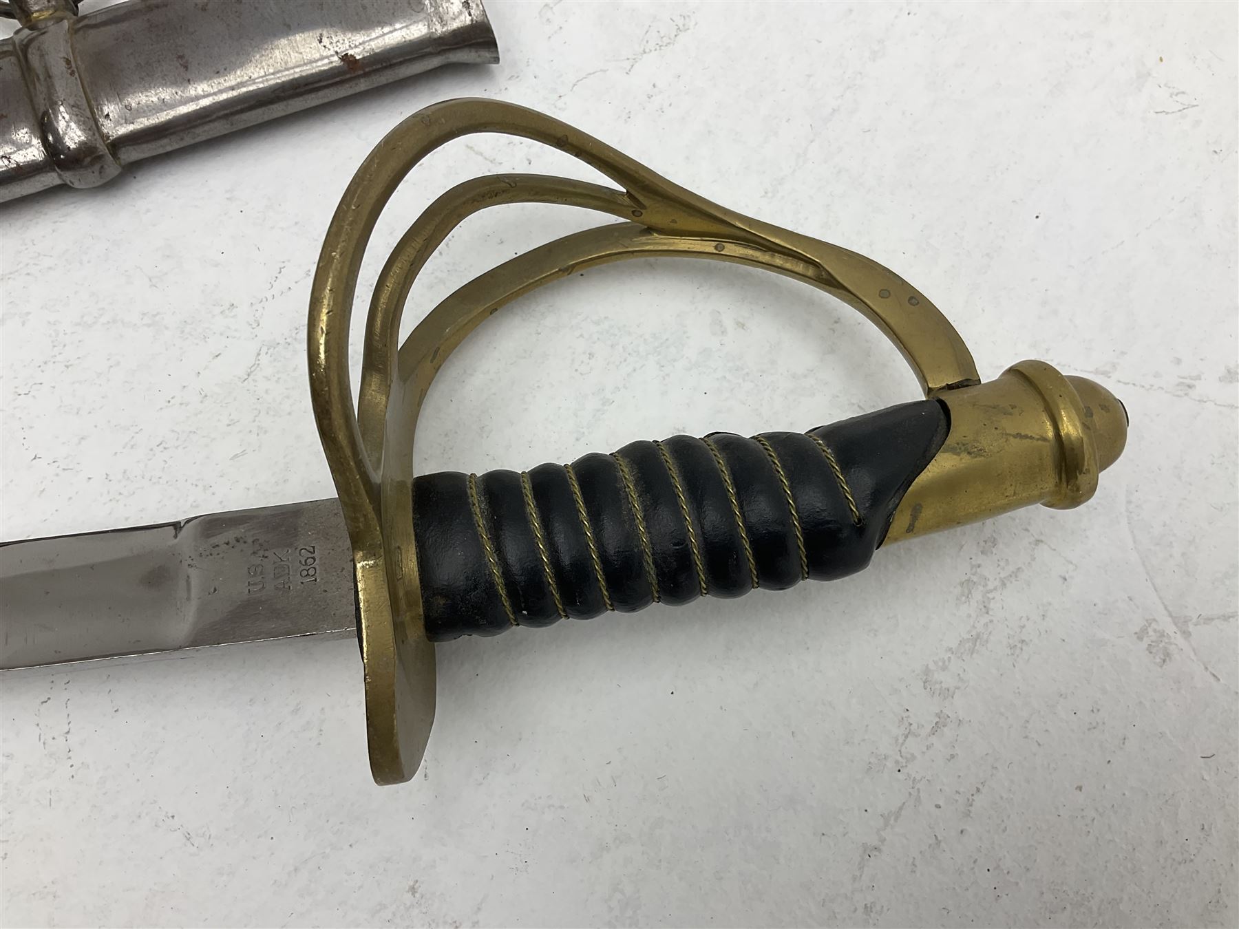 Reproduction American Civil War Cavalry trooper's sword, the 88cm slightly curving fullered steel blade marked to the ricasso 'Ames & Co Chicopee Mass.' and 'US ADK 1862'; brass hilt and leather covered grip; in steel scabbard L110cm overall;  and another reproduction sword (2)