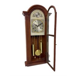 A contemporary Acctim (Anglo continental clock company) thirty-one day striking wall clock in a mahogany effect case with a fully glazed door displaying the pendulum and two dummy wights with chains, with a polished brass dial, Roman numerals, minute track and pierced steel hands, dial plate decorated with spandrels and Tempus Fugit inscribed on the dial brake-arch.
With key and pendulum.

