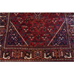 Central Persian Joshaghan hand-knotted carpet, deep red field decorated with a lattice design of stylized boteh and palmette motifs arranged around a stepped diamond medallion, navy corner spandrels similarly decorated enclosed by a dark indigo main border of floral and geometric motifs between multiple guard stripes, with cotton fringe ends 