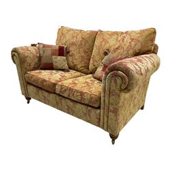 Duresta two seat sofa, upholstered in pale gold and rose fabric, mahogany feet; and matching rectangular footstool