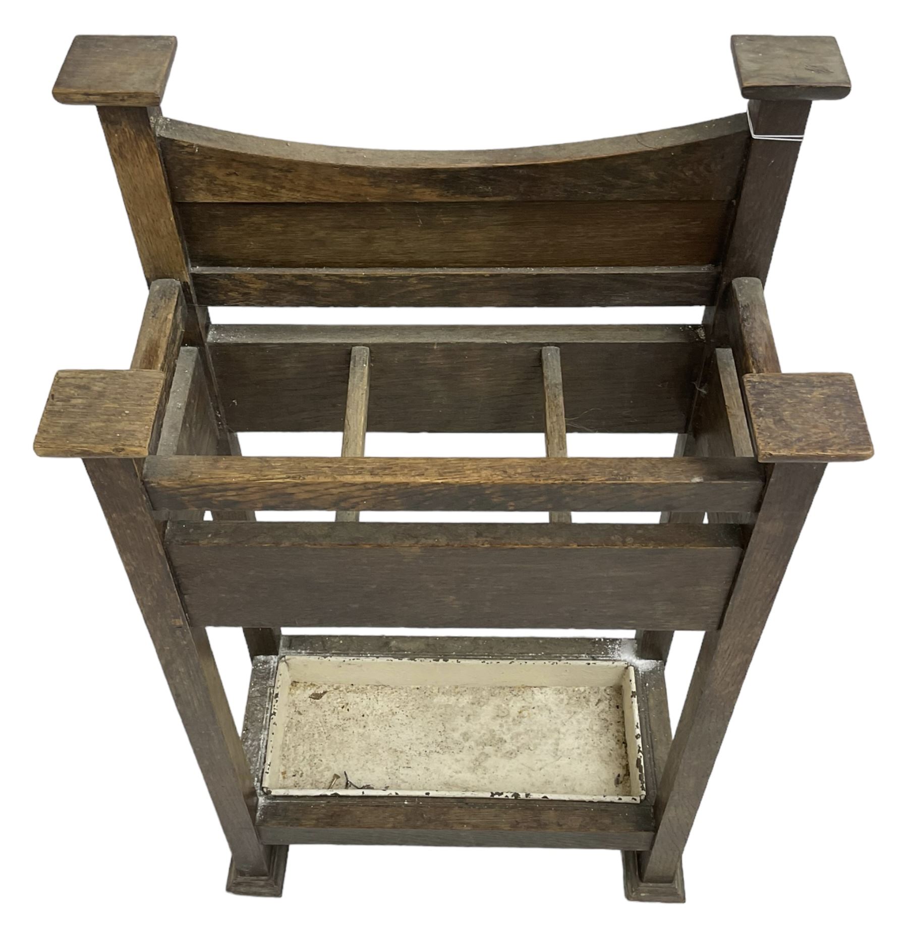 Early 20th century Arts & Crafts oak stick stand, panelled back over three divisions, fitted with metal drip tray, on square supports