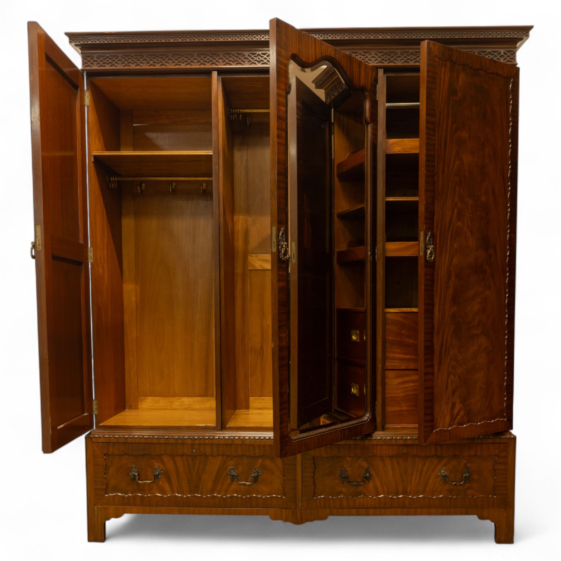 Waring and Gillow - Edwardian style figured mahogany three-section figured wardrobe, moulded and blind fretwork cornice, above three panelled doors, central door with bevelled mirror plate flanked by book-matched flame mahogany panels with moulded borders, above two long drawers with swan-neck handles, raised on bracket feet 