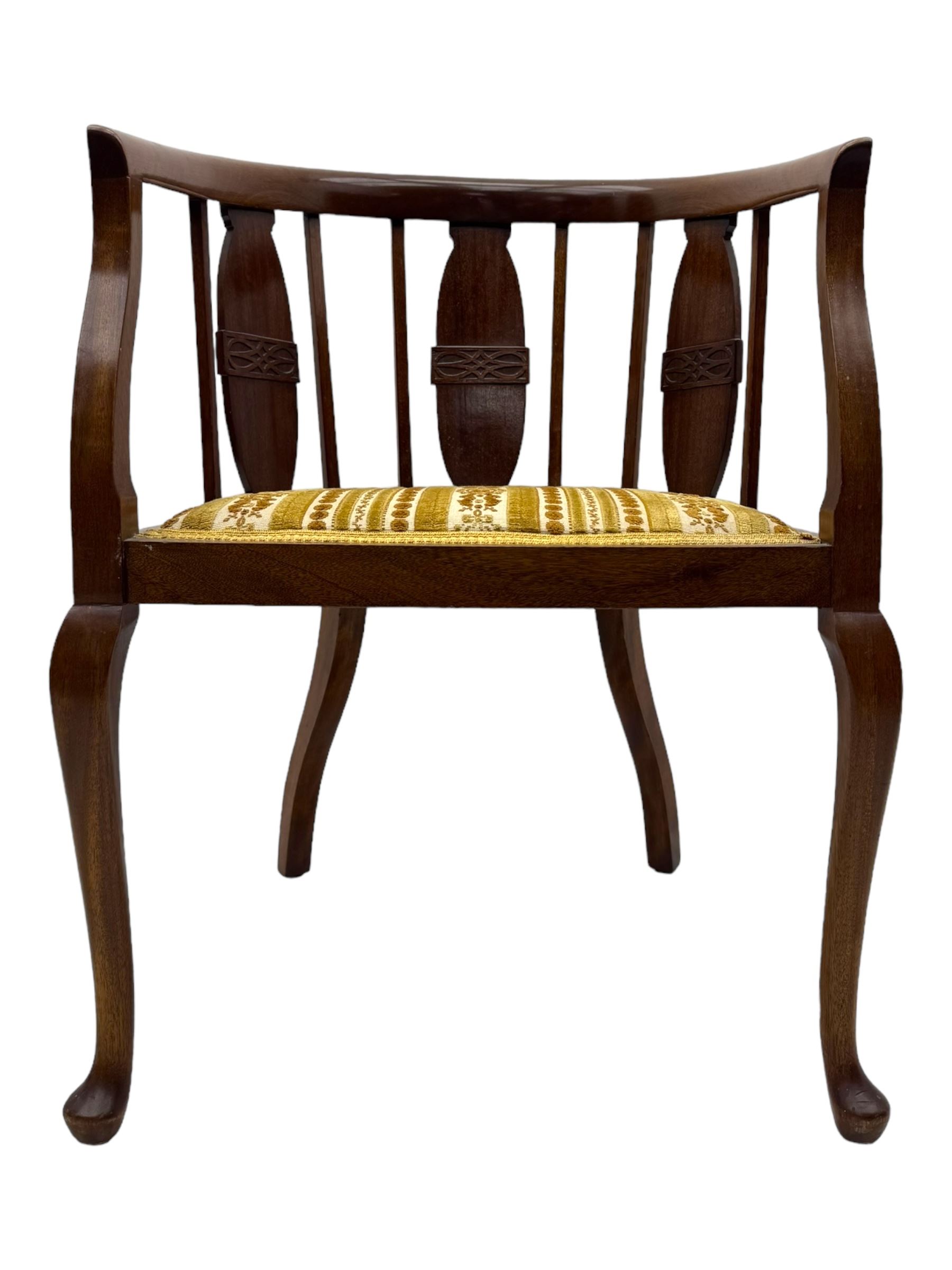 Late Victorian mahogany framed tub chair, rounded backrest with vertical splats and three carved oval medallions, upholstered seat in yellow patterned fabric, on cabriole supports