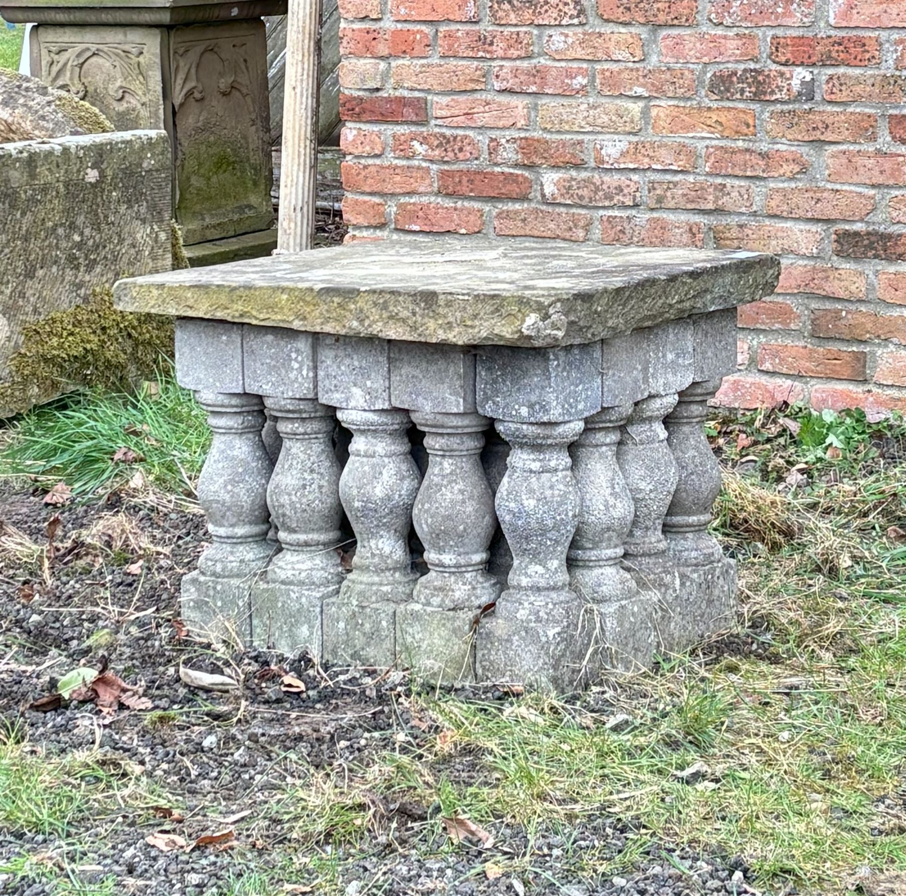 Weathered stone garden table, comprising twenty reconstituted stone balustrades supporting a stone flag top. H55cm, 63cm x 77cm.  - COLLECTION BY APPOINTMENT FROM: The White House, Thirsk Road, Easingwold, York, YO61 3NF - CALL 01723 507111 TO ARRANGE