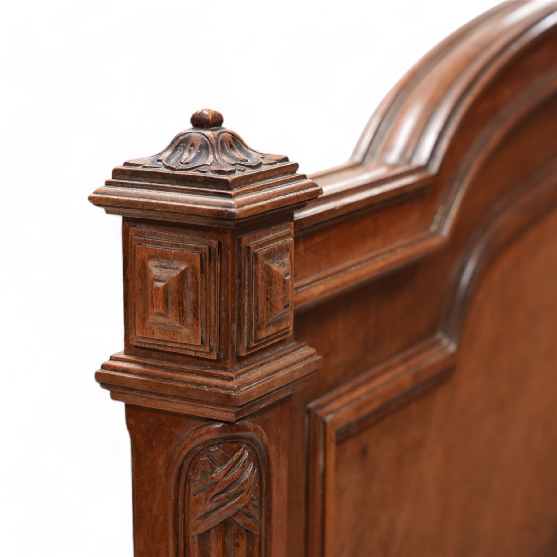 20th century French walnut 4' 6'' double bedstead, the headboard with flower head wreath pediment flanked by carved pineapple finials, reed and ribbon carved corner uprights, quarter-matched veneers, on turned feet, together with upholstered bed base