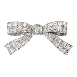 Art Deco white gold and platinum, milgrain set diamond bow brooch, stamped 18 & PT, the central cushion cut diamond of approx 0.20 carat, with old cut diamonds either side