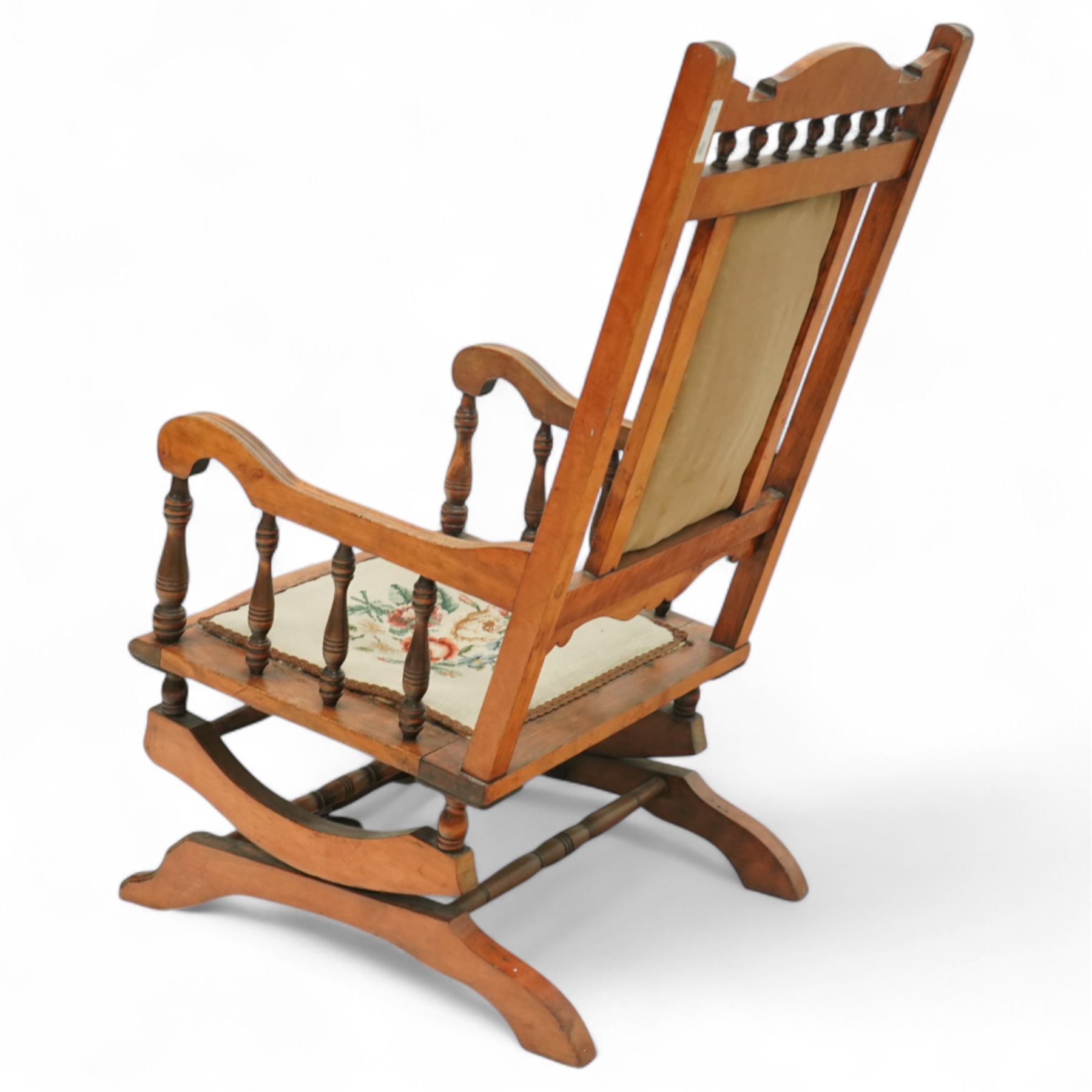 20th century American glider rocking chair, turned spindles to arms and backrest, with floral needlepoint upholstered back and seat, on spring-mounted glider base with shaped rockers