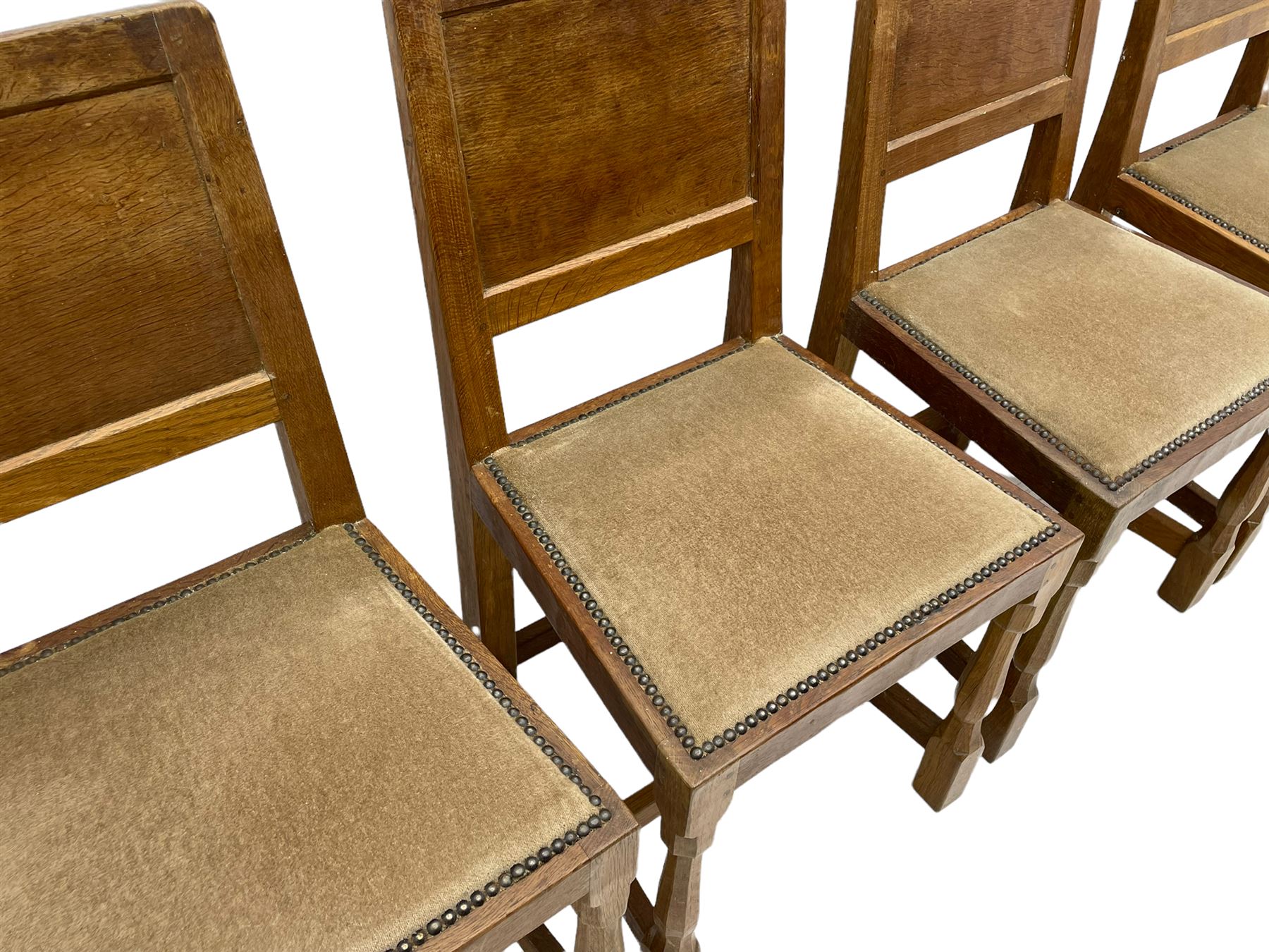 'Eagleman' set four oak dining chairs, adzed panelled backs, upholstered seats with stud work band, the side rails relief carved with inset eagle signature, shaped octagonal supports joined by stretchers, by Albert Jeffray of Sessay, Thirsk