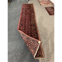 Central Asian runner rug, with repeating lozenge motif on busy red field, stylised foliate to border, 86cm x 400cm