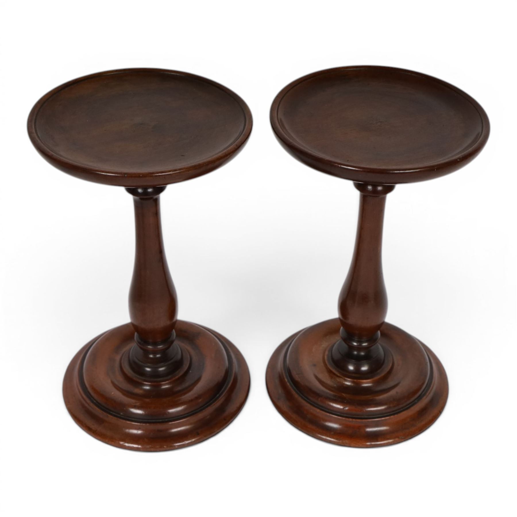 Pair of 19th century turned mahogany candle stands, each with circular top upon a baluster stem and circular stepped base, H25.5cm