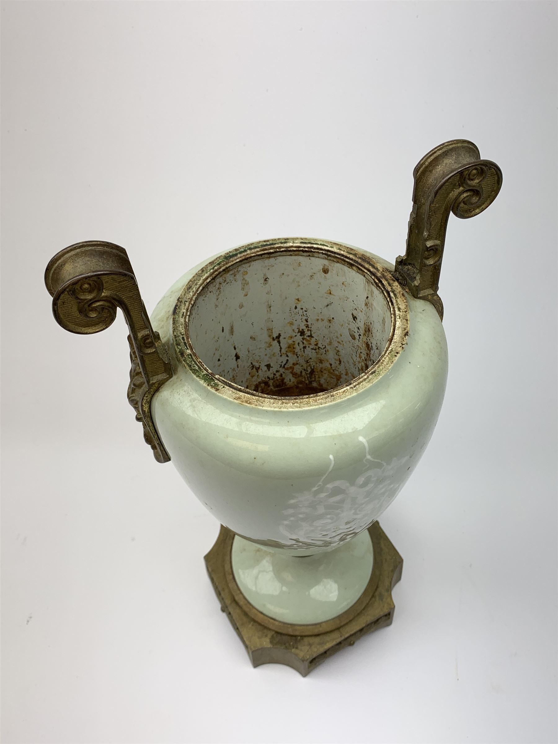 A pate sur pate celadon green vase, of baluster form decorated with a classical female figure to one side, and floral swag with ribbon and musical trophy to the other, with twin gilded scroll handles, and raised upon a gilded base, overall H38.5cm. 