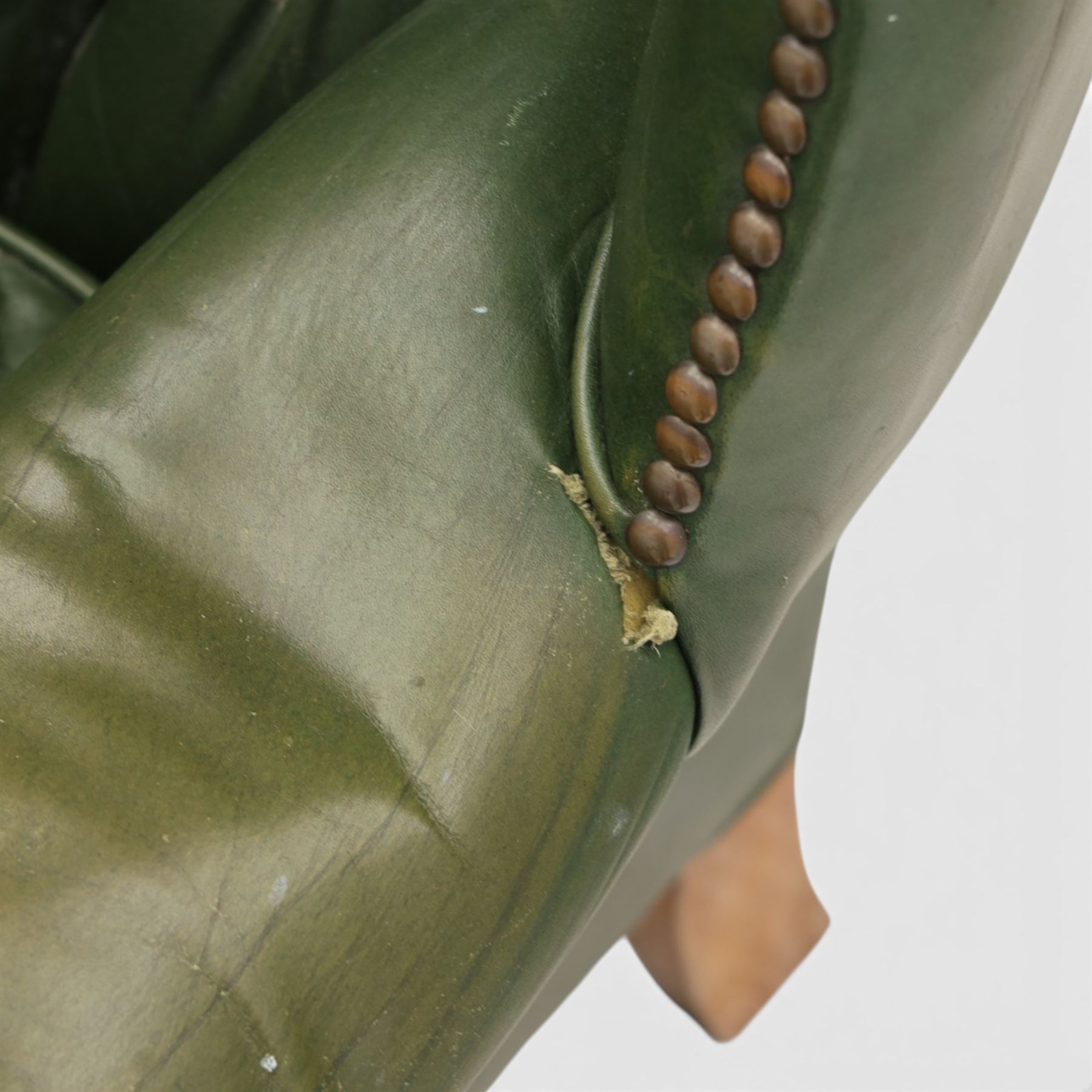 20th century green leather wingback button backed armchair, brass studded trim, with scrolled arms raised on oak supports