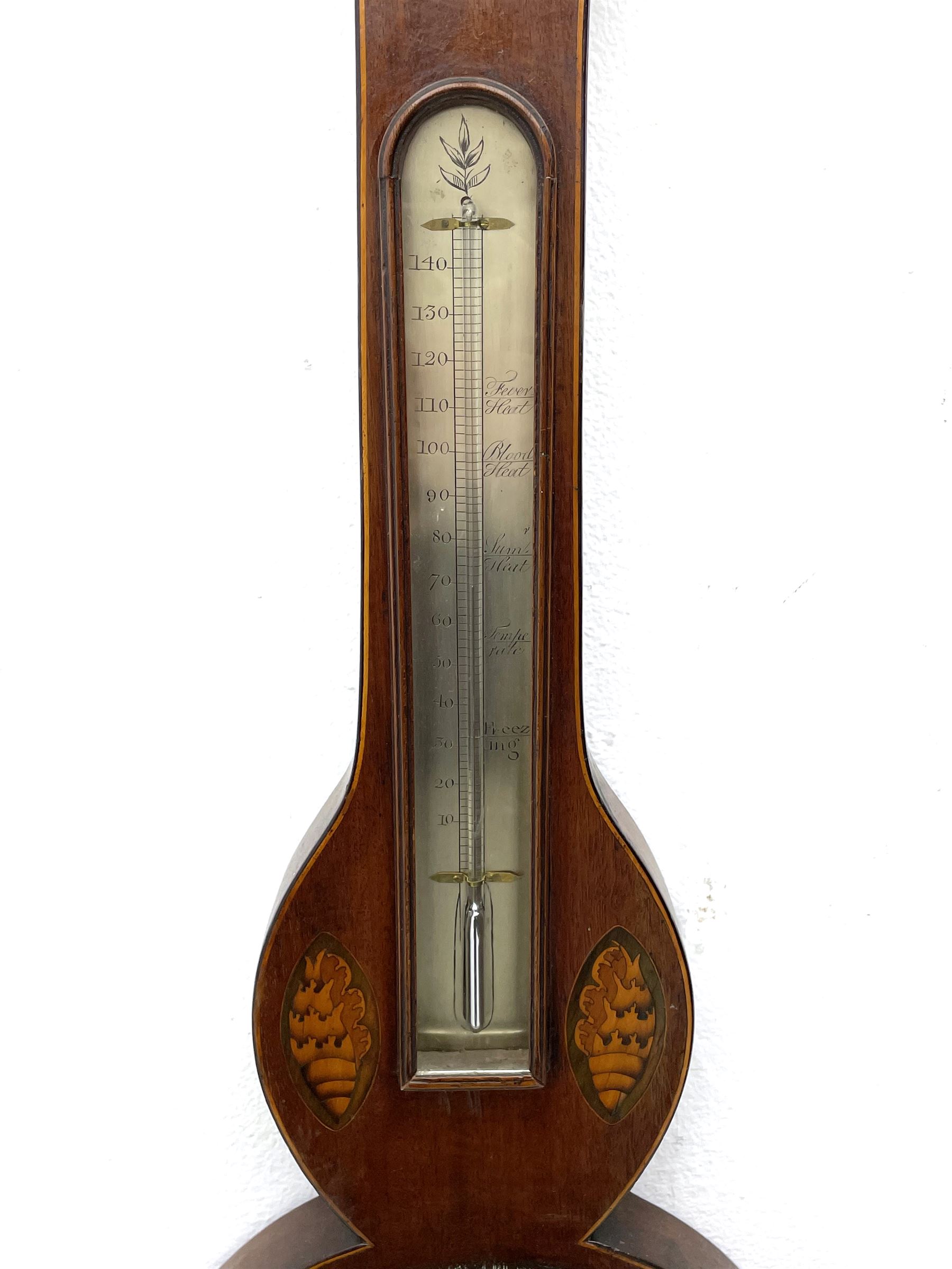 Early 19th century William IV mercury wheel barometer with a rosette inlaid broken pediment and correspondingly inlaid round base, mahogany veneered case with inlaid oval conch shell paterae and satinwood stringing to the edge, with an arched thermometer box and spirit thermometer measuring degrees Fahrenheit from 20 to 120, eight-inch silvered register reading barometric pressure in inches from 28  to 31, with predictions in Roman upper and lower case and script, dial inscribed “A Tagliabue,24 Grenville Street, Luther Lane, London”, with a steel indicating hand, brass recording hand and cast brass bezel.