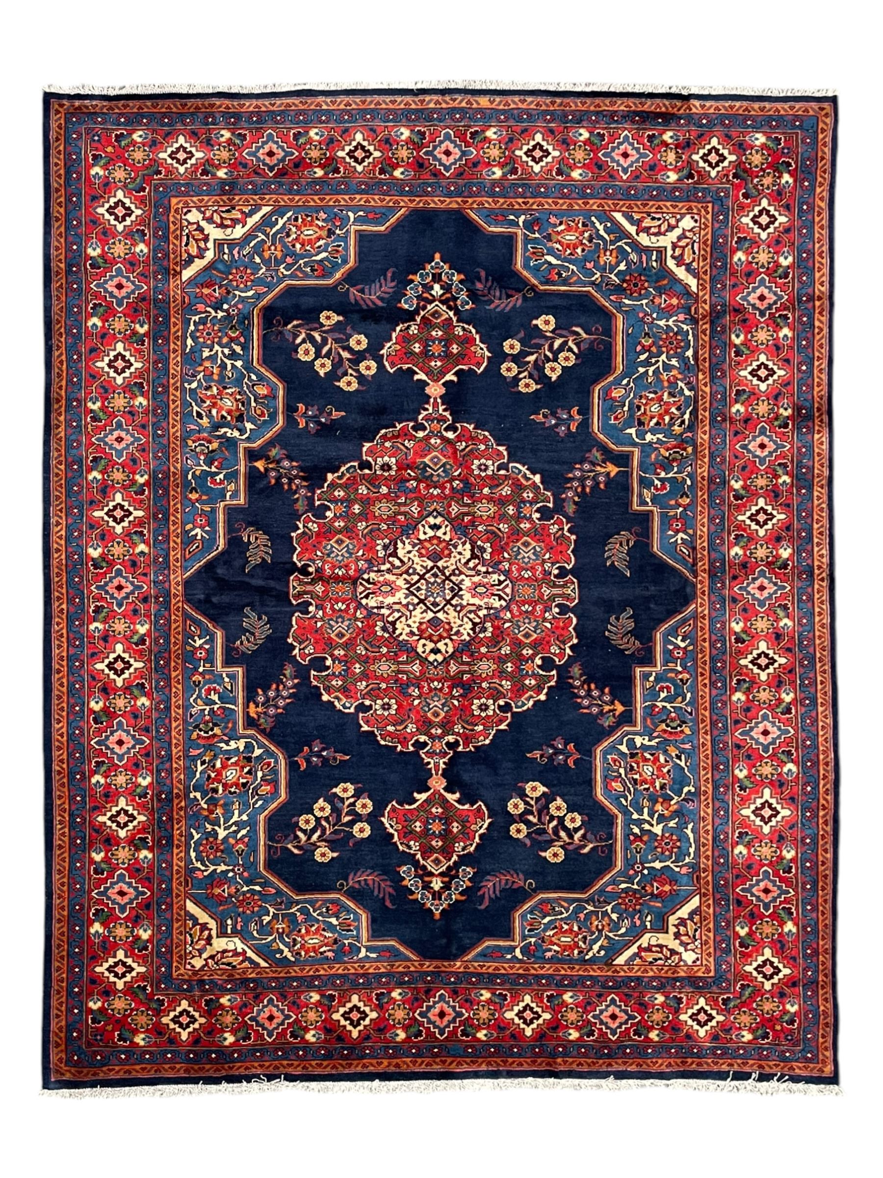 Persian Veis indigo ground carpet, the field with large pole medallion decorated with Herati motifs and surrounded by floral sprays, crimson ground border with repeating cross motifs and stylised flower heads, within guard stripes 
